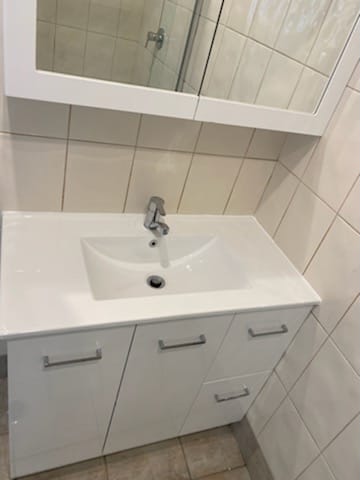 A newly fitted white bathroom vanity with basin and mirror cabinet